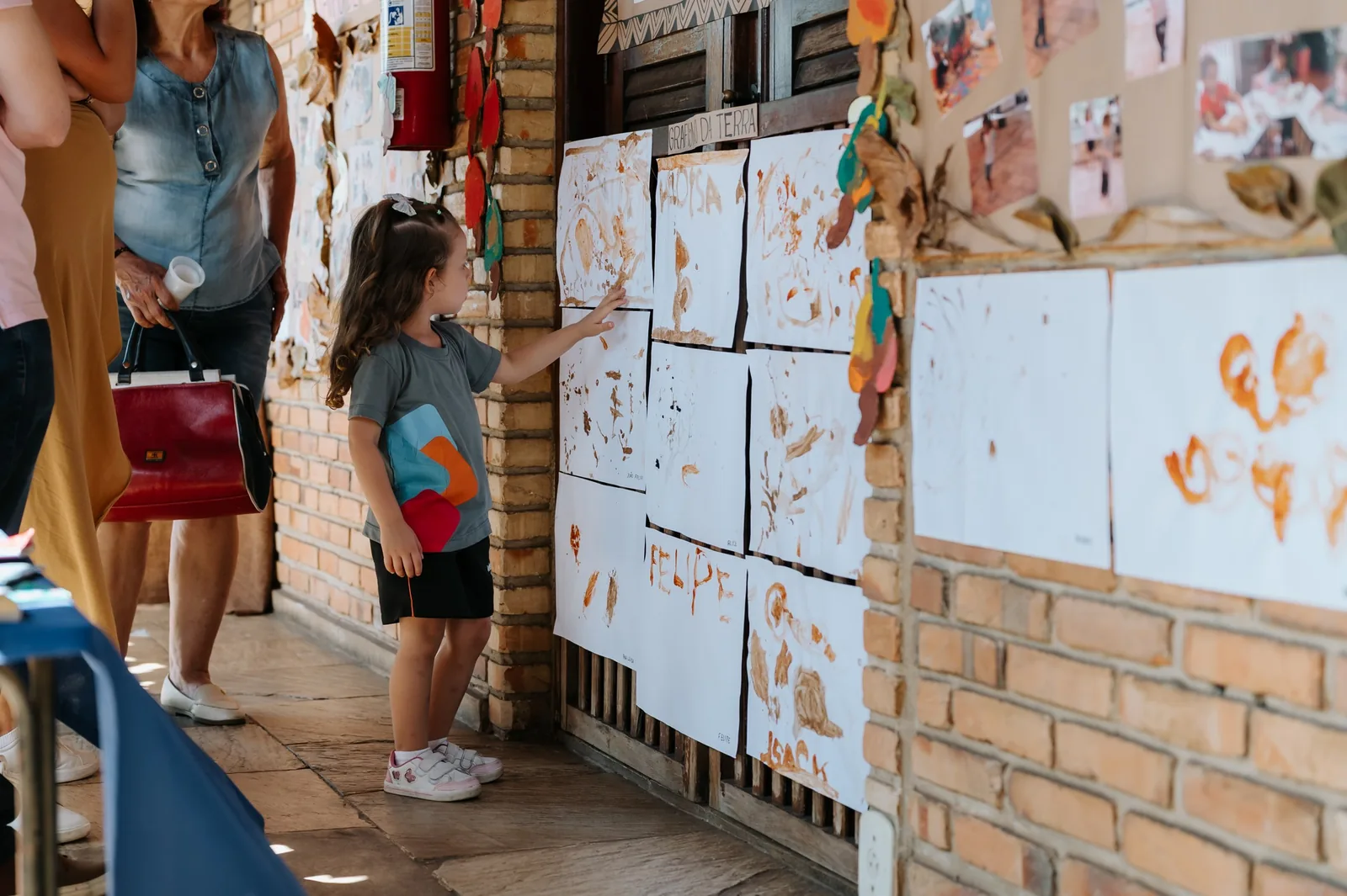 Criança observa pinturas e registros expostos no ateliê
